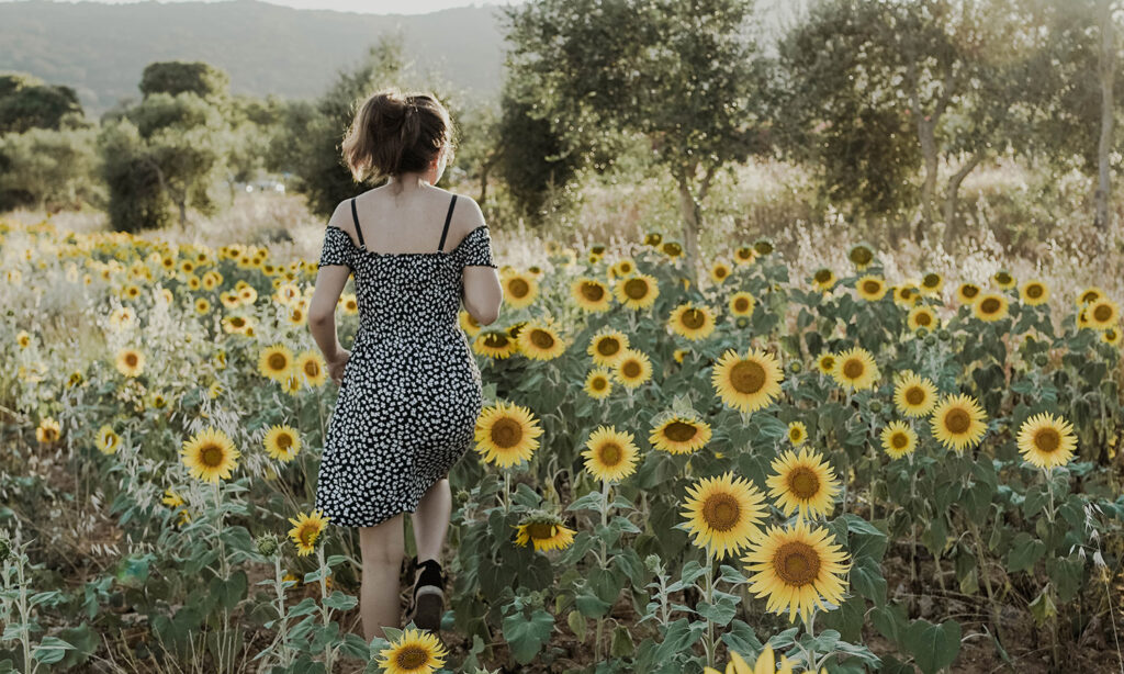 Dziewczyna w sukience biegnie przez słoneczniki